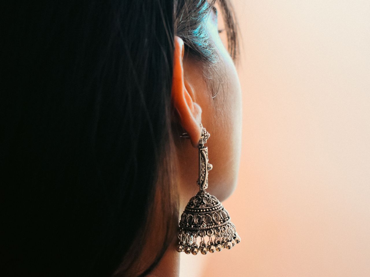 Detailed view of a woman's ear adorned with intricate silver earring.